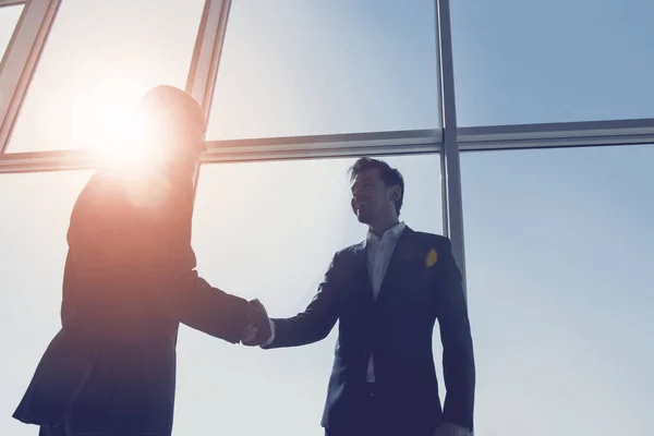 View from below of two young businessmen are standing in modern office with panoramic windows — Stock Photo, Image