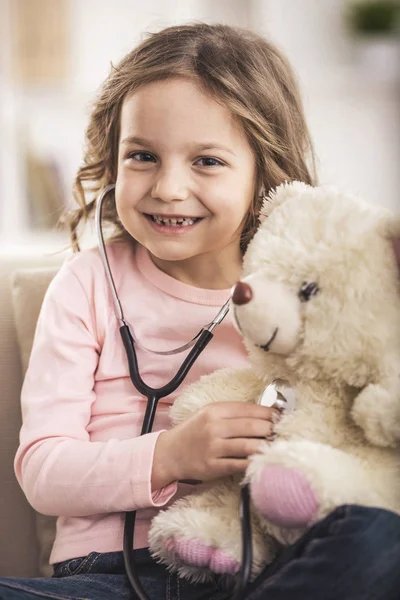 Linda niña con oso de peluche y estetoscopio —  Fotos de Stock