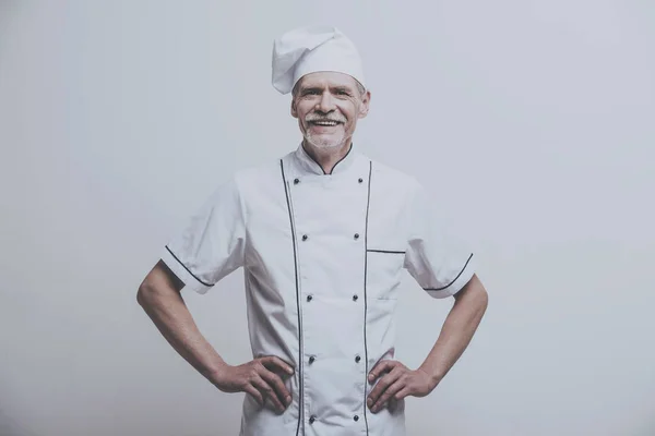 Senior male chief cook i uniform på grå bakgrund — Stockfoto