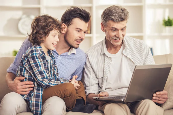 Generációs portré. Nagyapa, apa és fia, ült, és használ a laptop a kanapé — Stock Fotó