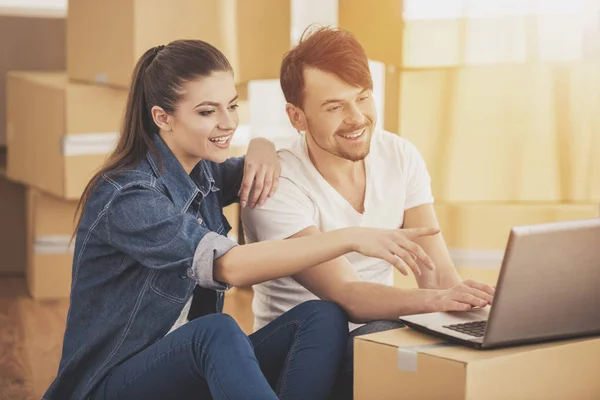 Das junge glückliche Paar auf der Suche nach Wohnungen mit Laptop. Umzug, Kauf einer neuen Wohnung — Stockfoto