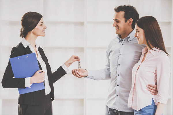 Female realtor is giving to young couple a key from new flat