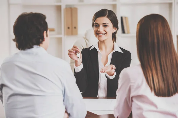 Female realtor with key and young couple from back — Stock Photo, Image