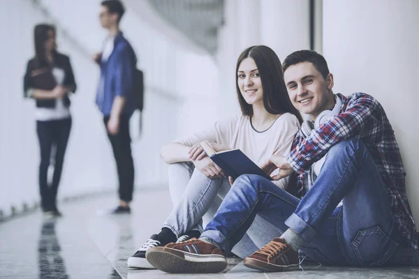 Jovens estudantes casal sentado no corredor na faculdade — Fotografia de Stock