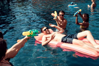 Genç arkadaş şirket çekim su silah içine havuzda. Yüzme havuz partisi. Bir grup insan yüzme havuzunda eğlenceli yaşıyorsanız.