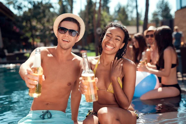 Young Man Sunglasses Cheerful Woman Cheering Beer Bottles Swimming Pool — 스톡 사진