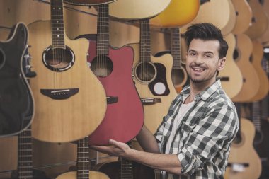 Adam arıyor ve gitar müzik dükkanında tutuyor