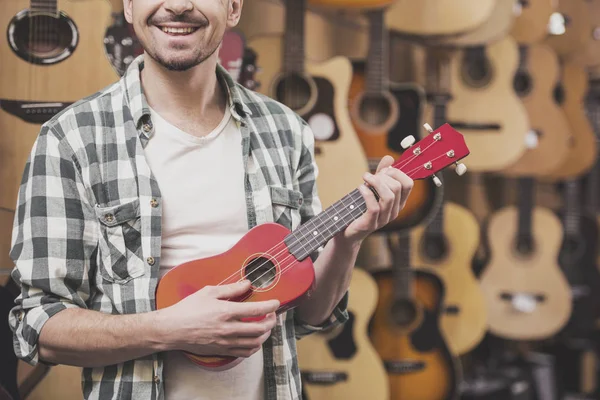 Primer plano. El hombre está sosteniendo ukelele rojo en la tienda de música — Foto de Stock