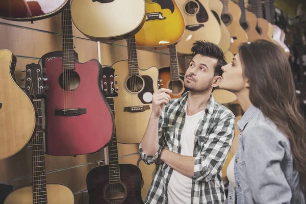 Άνδρας και γυναίκα εξετάζουν ένα κιθάρες σε ένα κατάστημα μουσικής — Φωτογραφία Αρχείου