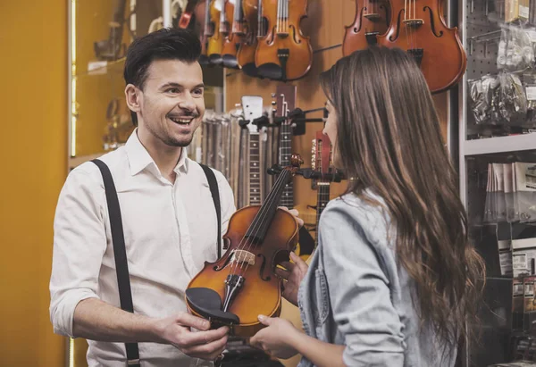 年轻的女孩正在买一把小提琴在音乐商店. — 图库照片