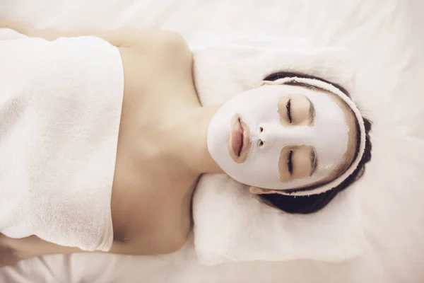 Spa therapy for young asian woman receiving facial mask at beauty salon — Stock Photo, Image