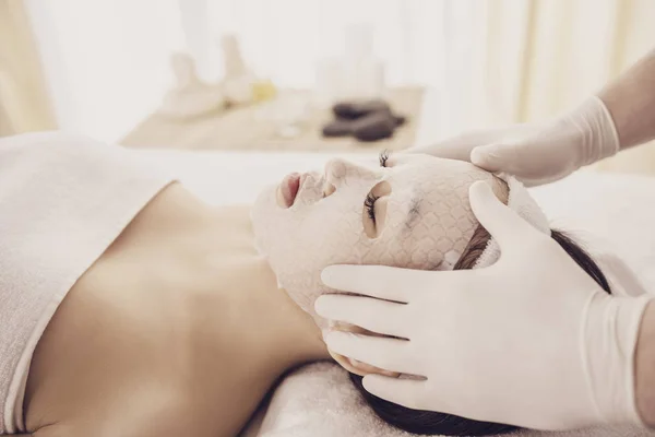 Terapia de spa para jovem mulher asiática recebendo máscara facial no salão de beleza — Fotografia de Stock