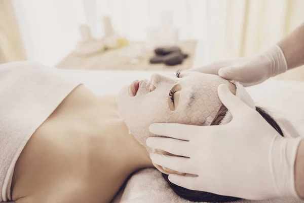 Spa therapy for young asian woman receiving facial mask at beauty salon — Stock Photo, Image