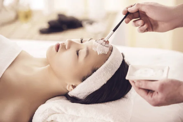 Spa therapy for young asian woman receiving facial mask at beauty salon — Stock Photo, Image