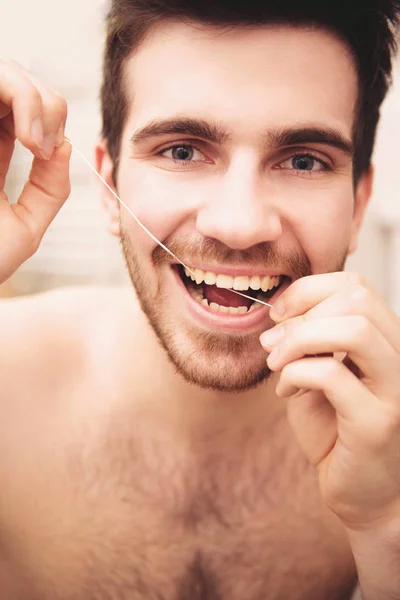 Člověk je flossing zuby v koupelně ráno. — Stock fotografie