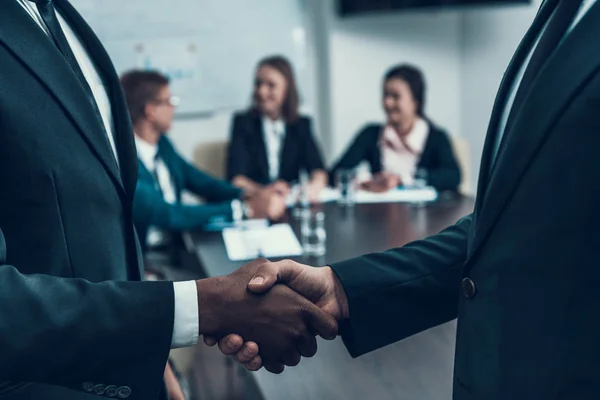 Two successful multi ethnic businessmen make deal with firm handshake. — Stock Photo, Image