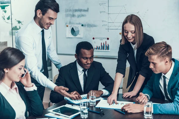 Empresaria exitosa le dice a sus colegas sobre el crecimiento de las acciones de la empresa, apuntando a los gráficos . —  Fotos de Stock