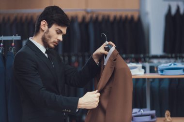 Ceket iş erkek giyim mağazası, kendine güvenen genç işadamı bakar.