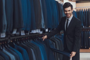 Ceketler erkek iş giyim mağazası showroom Satılık kendine güvenen genç adam bakar.