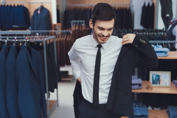 Successful young businessman measures jacket in business mens clothing store. — Stock Photo, Image