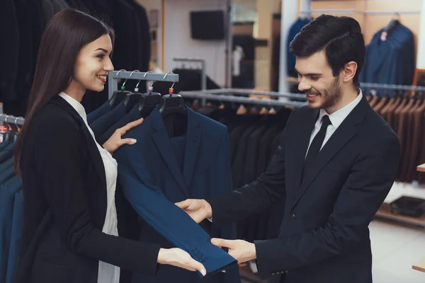 Jovem empresário bem sucedido olha para jaqueta, consultoria com consultor na loja. — Fotografia de Stock