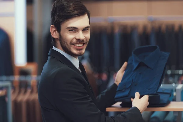 Joven empresario exitoso en traje elige camisa para comprar. Boutique de trajes de negocios . — Foto de Stock