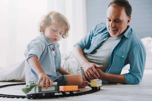 Pequeño rizado chico juega juguete tren con el abuelo . — Foto de Stock