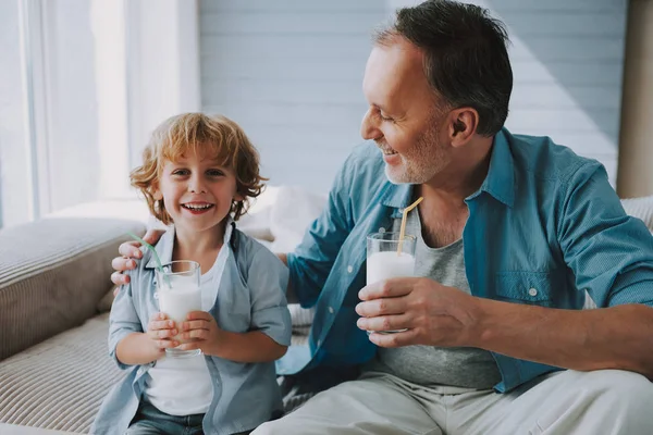 Mutlu küçük torunu içecekler saman ile süt bardakta dedesi ile. — Stok fotoğraf