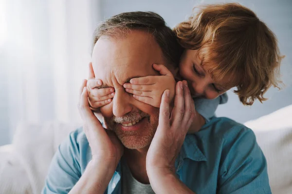 El nieto pequeño cierra con las manos los ojos del abuelo . — Foto de Stock