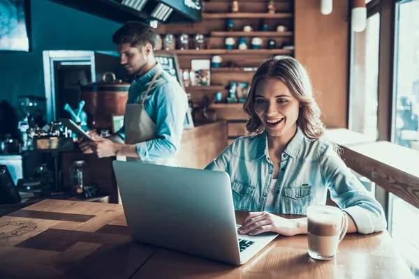 Alegre atractiva mujer está navegando por Internet en la cafetería . — Foto de Stock