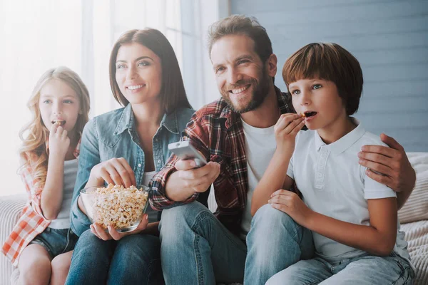 Lycklig familj titta på film tillsammans och äta popcorn medan hemma. — Stockfoto