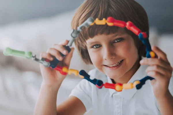 Cheerful kid sits with toy that develops logic. Educational toys. — Stock Photo, Image