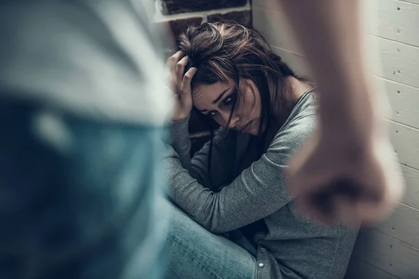 Mujer triste con moretones se sienta en la esquina de la habitación . — Foto de Stock