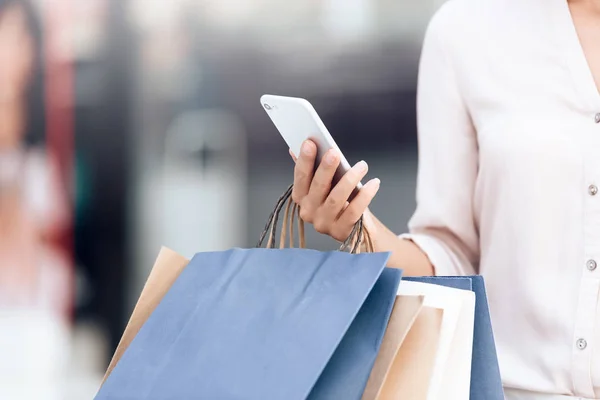 Femme avec sacs à provisions et smartphone dans le centre commercial . — Photo