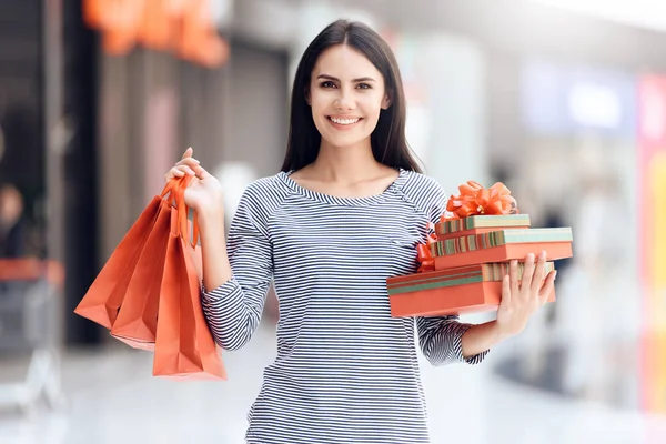 Brune heureuse avec des sacs à provisions et des boîtes-cadeaux dans le centre commercial . — Photo