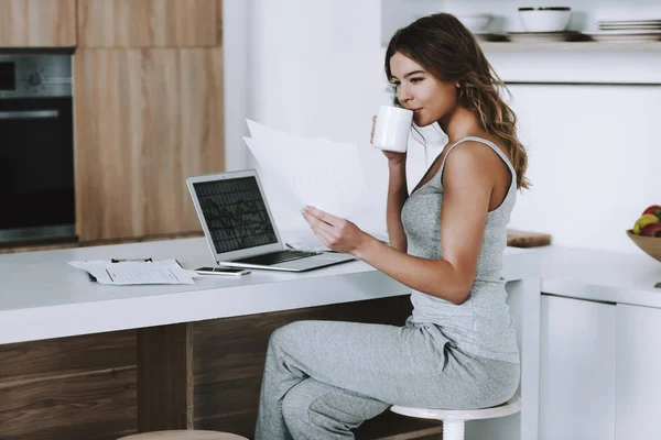 Giovane donna con tazza di caffè sta guardando notizie finanziarie . — Foto Stock