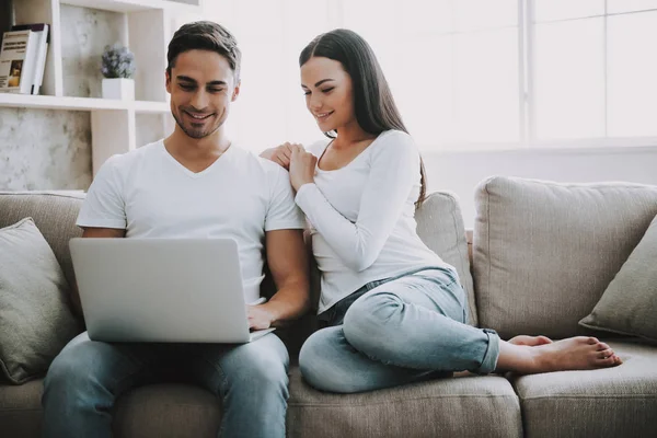Ungt par tillbringar fritid med laptop hemma. — Stockfoto