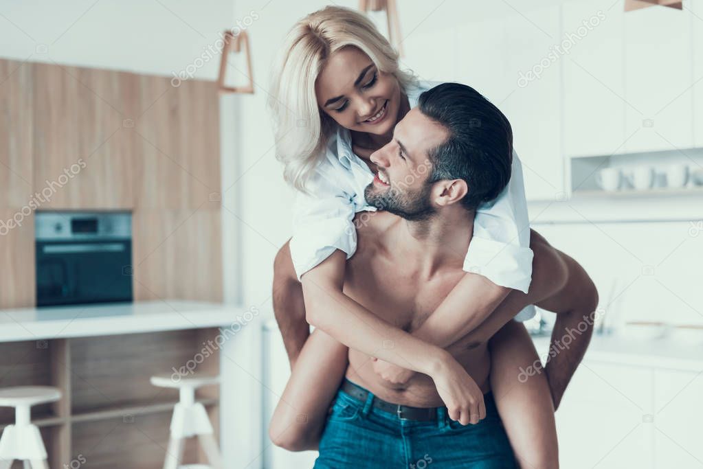 Handsome, muscular man holds beautiful blonde on piggyback.