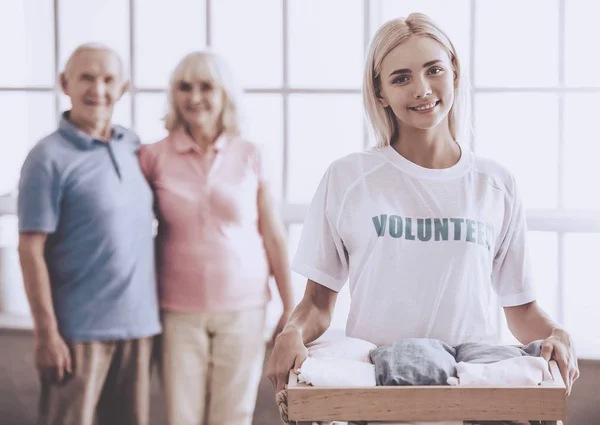 Beautiful Young Female Volunteer Holding Box New Clothes Old Couple Stock Image