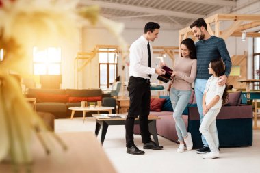 Mobilya mağazası Müdürü kumaşlar için mobilya döşeme örnekleri içerir. Ona bir anne, baba ve kız vardır. Onlar mobilya alıcılar vardır.