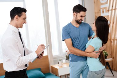 Genç çift, sarılma ve parlak bir ofiste birbirlerine gülümsüyor. Yakınlarda bir adam - bir mobilya mağazası bir satıcı olduğunu.