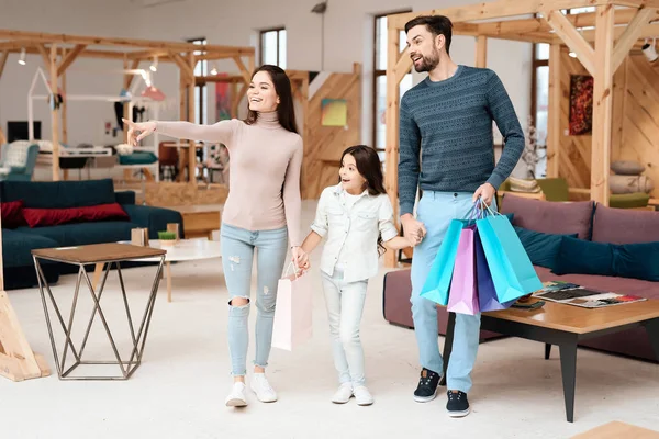 若い家族は 小さな女の子とは 家具店の周り歩いています 彼らは別のソファを見ています — ストック写真