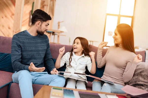 Küçük kız kanepe döşeme örnekleri ile oturan genç ailesiyle. Birlikte yeni ev mobilyaları seçmek için mobilya mağazası için geldiler.