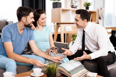 İki erkek ve bir kadın yeni mobilya alımı görüşüyorlar. Dükkana gelen genç bir ailedir. İyi bir ruh halinde oldukları.