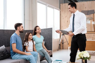 Bir aile küçük bir kız ile bir mobilya mağazasında kanepede oturuyor. Yanlarında bir yöneticisidir. Onlar farklı dokuların düşünün.