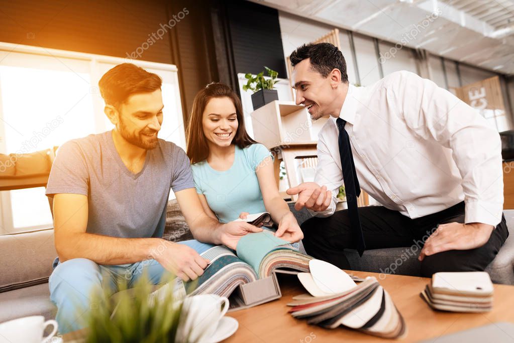 Two men and a woman are discussing the purchase of new furniture. This is a young family who came to the store. They are in a good mood.