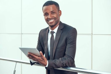 Afrikalı İşadamı Tablet üzerinde çalışıyor ve gülümsüyor.