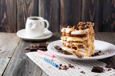 Ev yapımı pasta kek ve beze, ceviz, eski ahşap zemin üzerine koyu çikolata katmanlı.