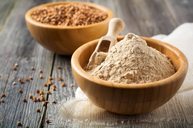 Eski ahşap arka plan üzerinde bir bambu kapta buğday unu.