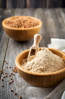 Eski ahşap arka plan üzerinde bir bambu kapta buğday unu.